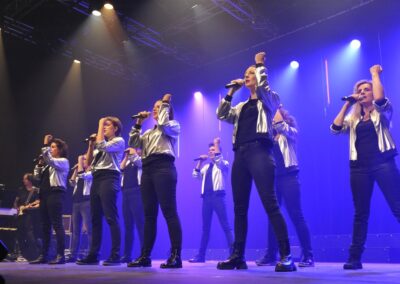 Groupe chantant sur scène avec vestes argentées