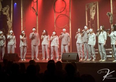 Groupe de chanteurs masqués sur scène.