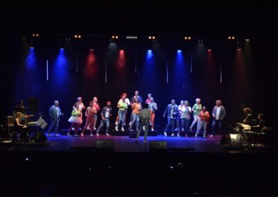 Groupe de personnes sur scène avec éclairage coloré.