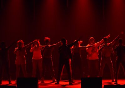 Groupe de personnes dansant sur scène éclairée en rouge